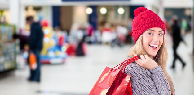 Composite image of festive blonde holding shopping bags