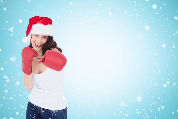 Composite image of festive brunette in boxing gloves punching