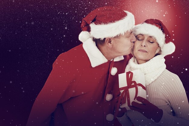 Composite image of festive mature couple holding gift