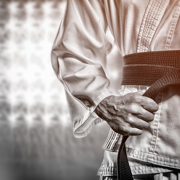 Composite image of fighter tightening karate belt