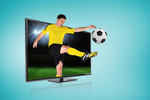 Composite image of football player kicking ball through tv against football pitch under spotlights