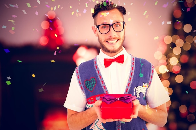 Composite image of geeky hipster offering christmas gift