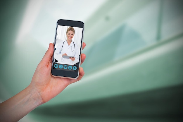 Composite image of hand holding mobile phone against white background