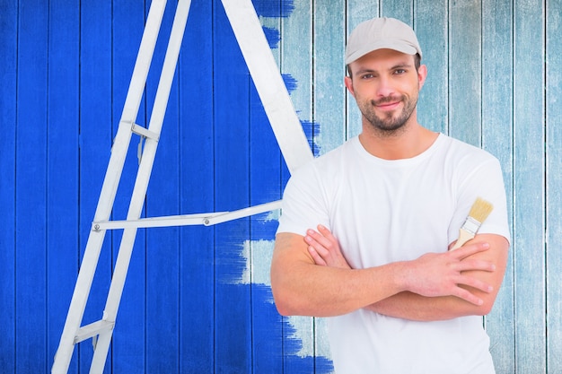 Composite image of handyman with paintbrush and ladder