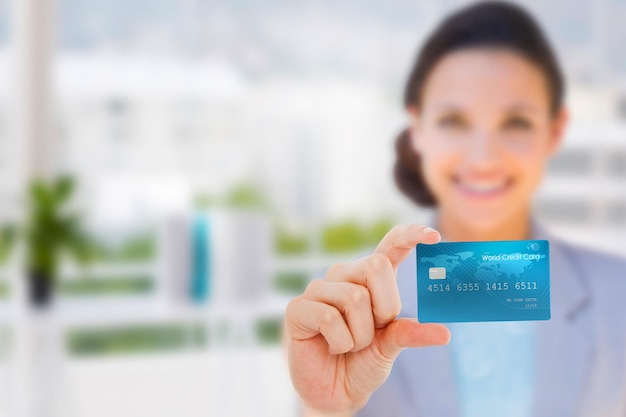 Composite image of happy businesswoman showing a creditcard