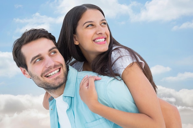 Composite image of happy casual man giving pretty girlfriend piggy back