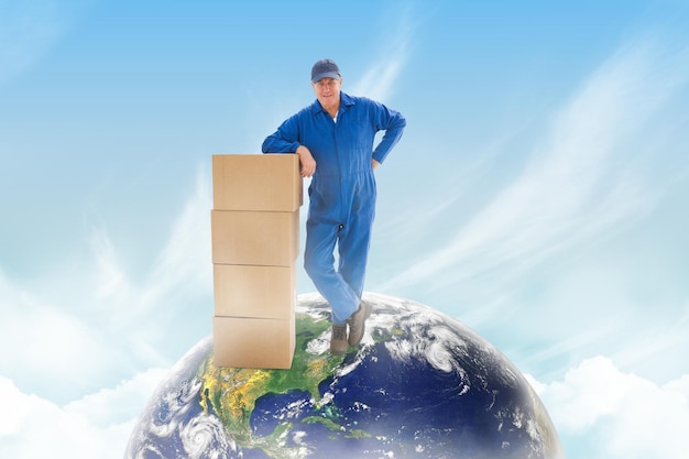 Composite image of happy delivery man leaning on pile of cardboard boxes