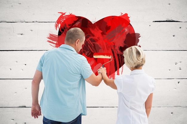 Composite image of happy older couple painting white wall