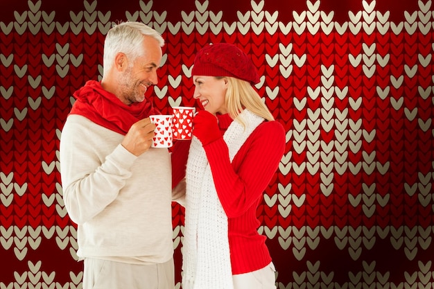 Composite image of happy winter couple with mugs