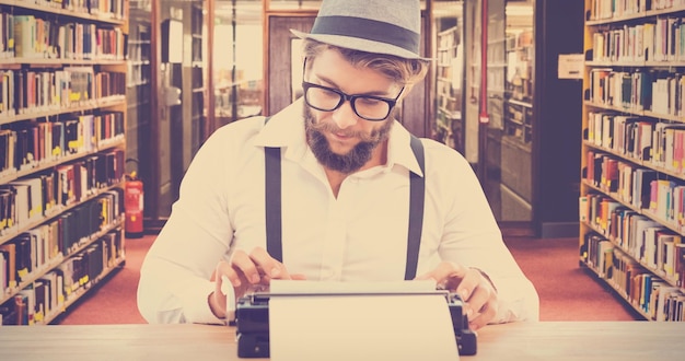 Composite image of hipster wearing eye glasses and hat working on typewriter