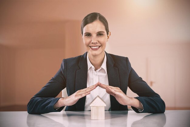 Composite image of insurer protecting a house by his hands