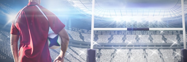 Composite image of male rugby player holding rugby ball in the ground