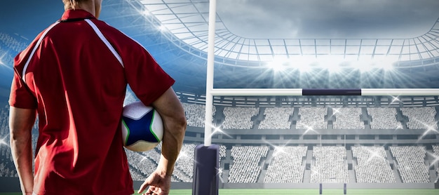 Composite image of male rugby player holding rugby ball in the ground