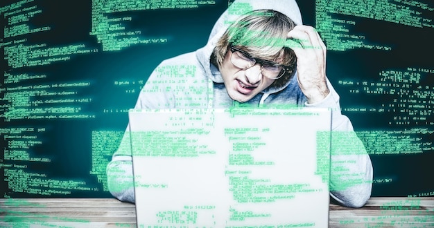 Foto immagine composita dell'uomo in giacca con cappuccio che hackera un computer portatile