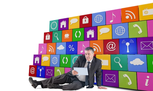 Composite image of mature businessman sitting using tablet