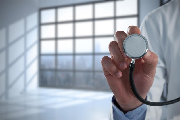 Composite image of mid-section of male doctor using stethoscope