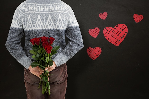Composite image of mid section of man hiding red roses