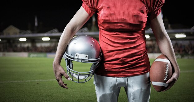 Composite image of mid section of sportsman holding american football and helmet