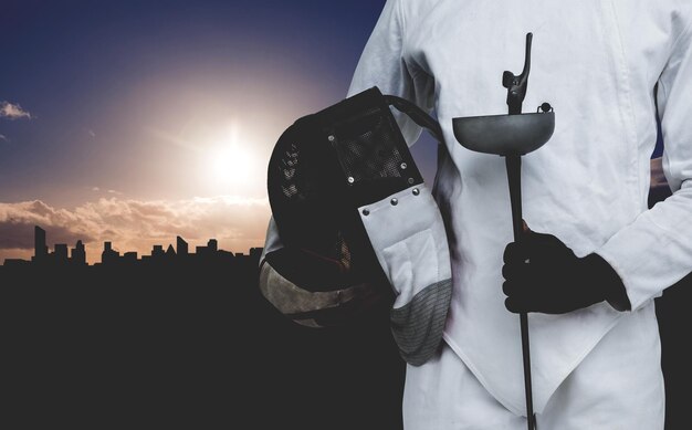 Composite image of midsection of man standing with fencing mask and sword