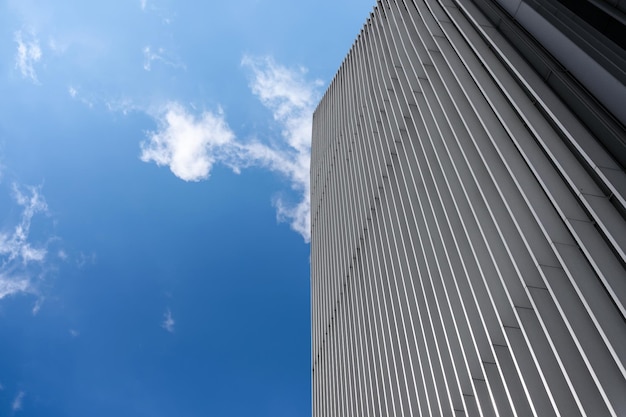 Композитное изображение современного архитектурного фона металлического небоскреба на фоне голубого неба и кучевых облаков