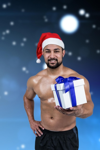 Composite image of muscular man in santa hat