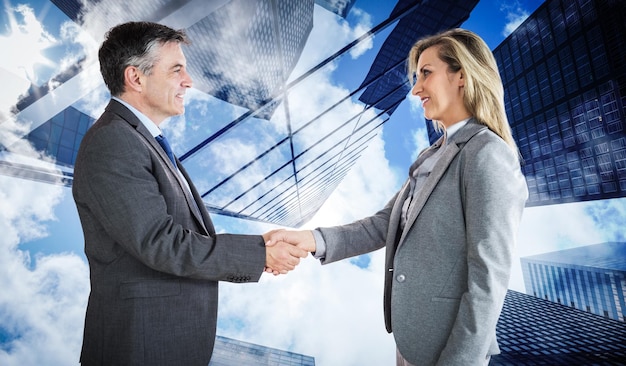 Composite image of pleased businessman shaking the hand of content businesswoman