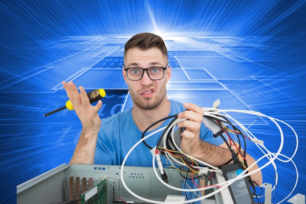 Photo composite image of portrait of confused young it professional with screw driver and cables in front of open cpu