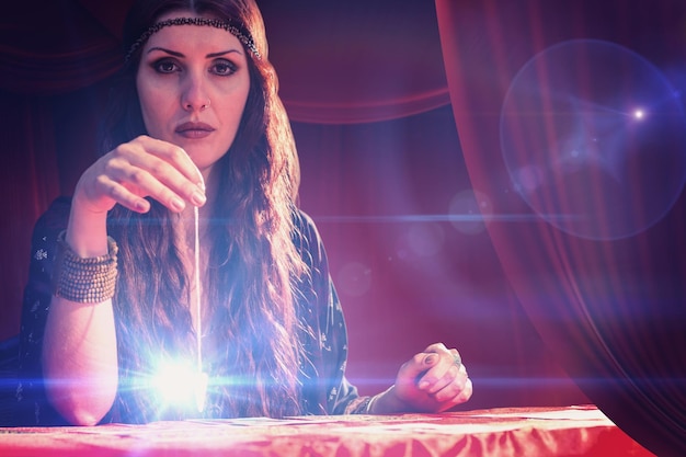 Composite image of portrait of fortune teller with pendulum