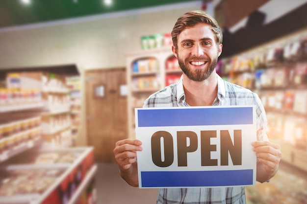 Composite image of portrait of happy male owner holding open sign