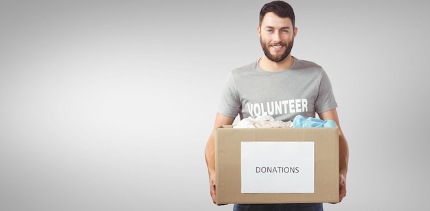 Composite image of portrait of man holding clothes donation box in office