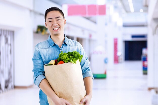 Composite image of portrait of man with grocery bag