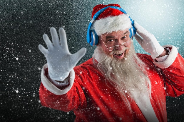 Composite image of portrait of santa claus listening to music on headphones