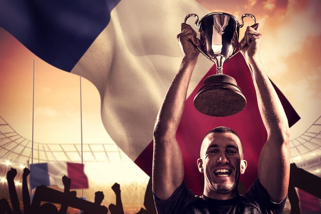 Composite image of portrait of successful rugby player holding trophy