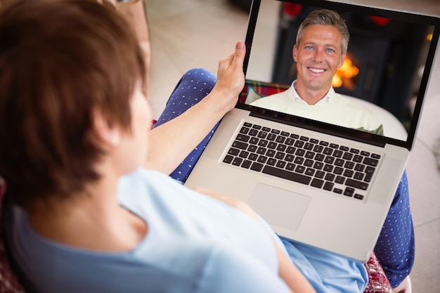 Immagine composita della donna incinta che usa il suo laptop