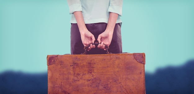 Composite image of rear view of hipster woman holding suitcase