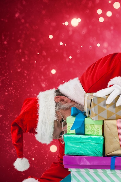 Composite image of santa claus hiding behind christmas gifts