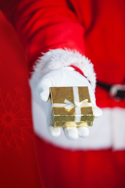 Composite image of santa claus holding gift box in hand