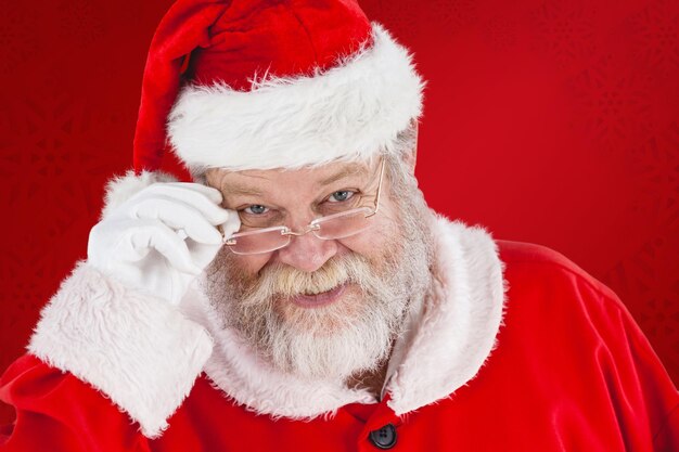 Composite image of santa claus holding spectacles