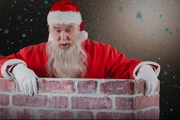 Composite image of santa claus peeking over wall