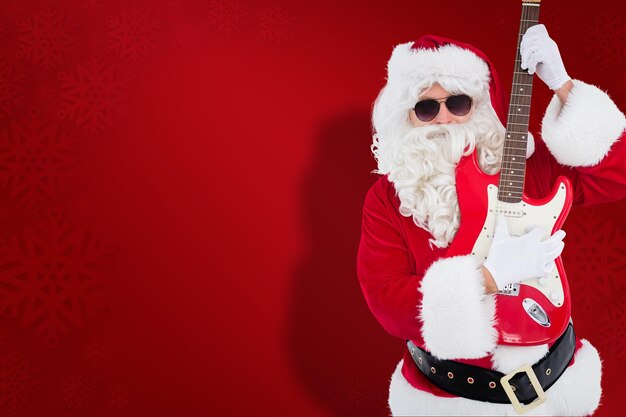 Composite image of santa with sunglasses playing electric guitar