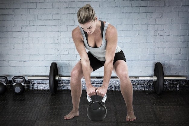 Photo composite image of serious muscular woman lifting kettlebell