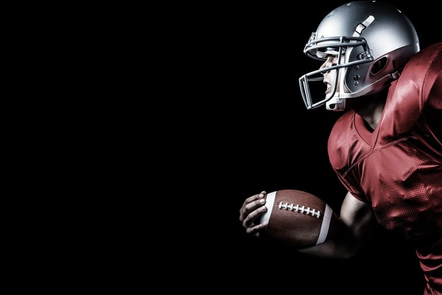 Composite image of side view of aggressive sportsman playing american football