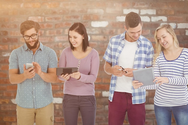 Composite image of smiling business people using electronic gadgets