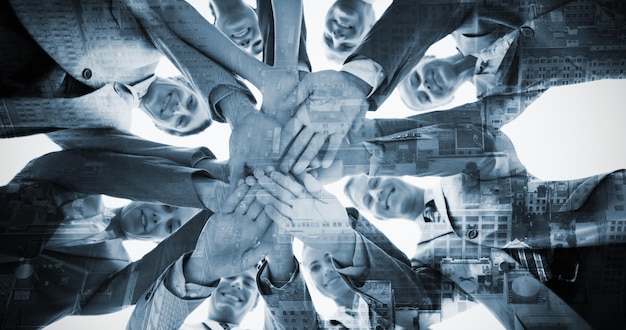 Composite image of smiling business team standing in circle hands together