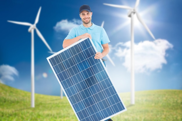 Composite image of smiling construction worker holding solar panel