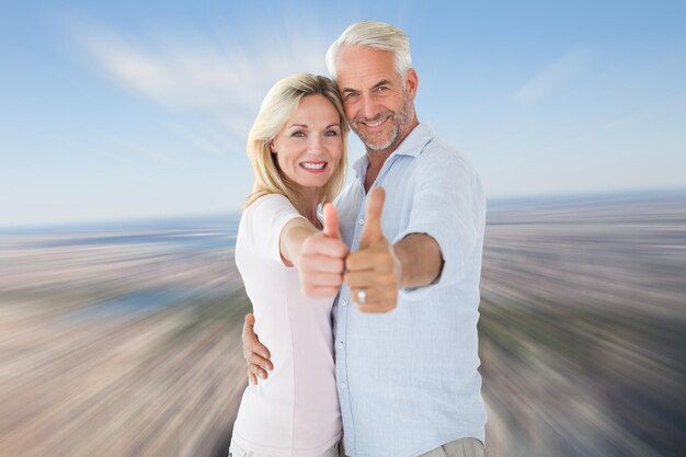 Composite image of smiling couple showing thumbs up together