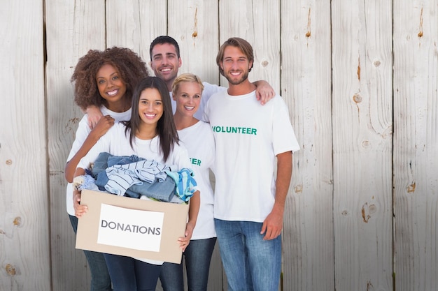 Composite image of smiling group of volunteers holding donation box