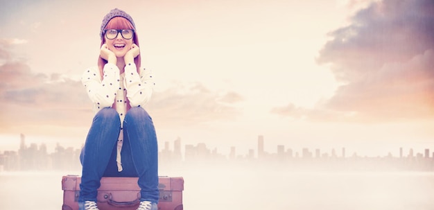 Composite image of smiling hipster woman sitting on suitcase