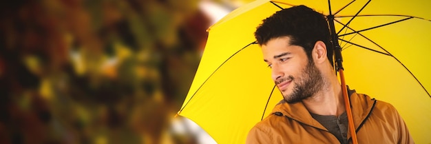 Composite image of smiling man holding yellow umbrella