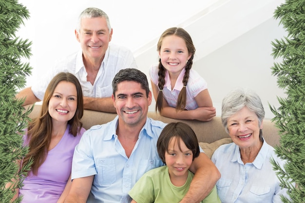 Composite image of smiling multigeneration family against green fir branches